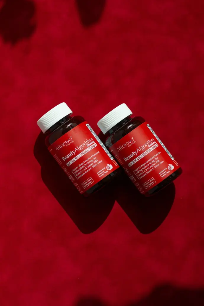Two bottles of vitamins sitting on a red surface